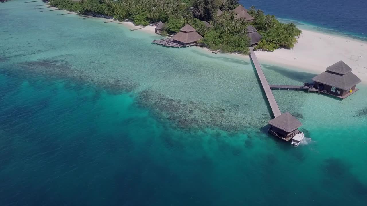 空中摇摄摩托艇停泊在度假码头在晴朗的一天，无人机飞越蓝色的海-瓦都，马尔代夫视频下载