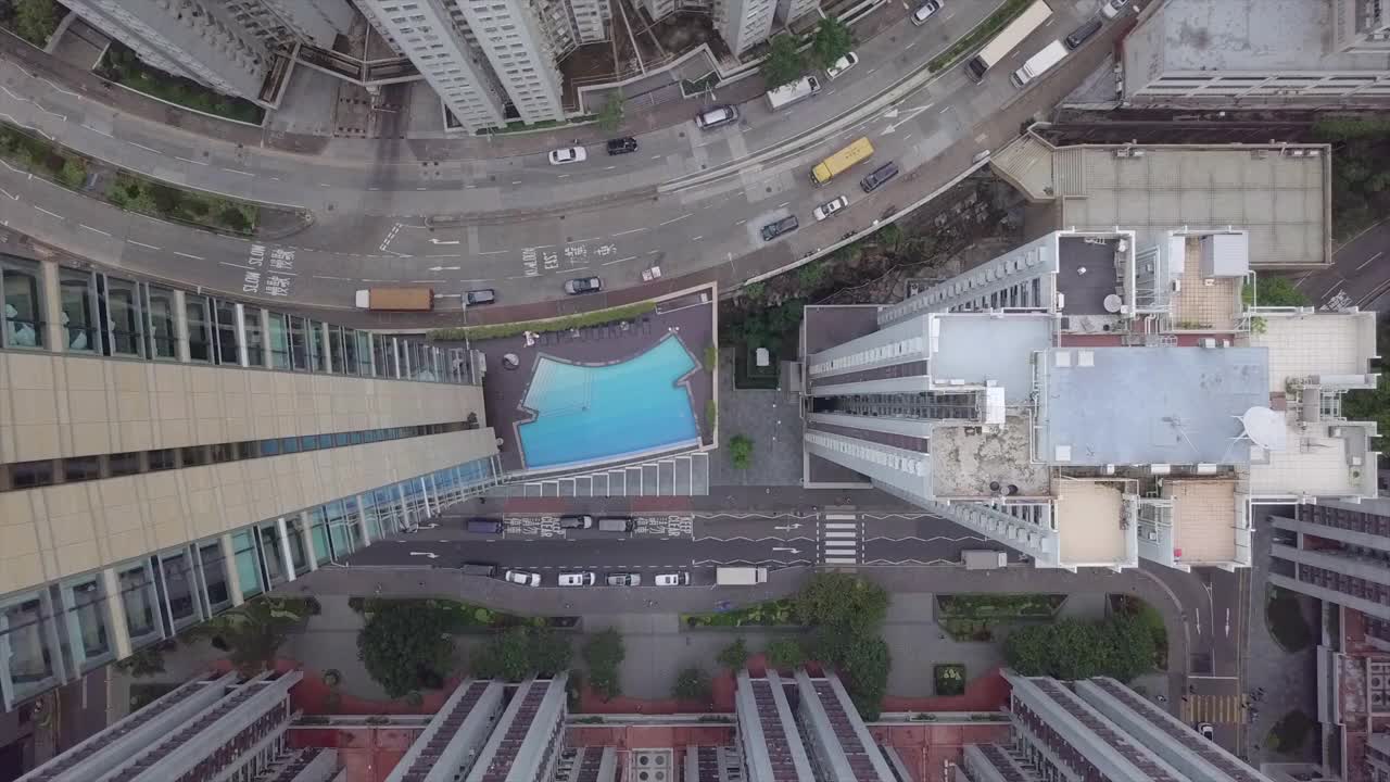 空中俯瞰在建筑物中游泳的人，无人机下降在街道上的车辆在城市-香港，中国视频素材