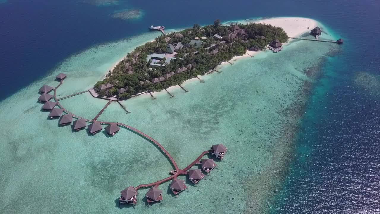 航拍的豪华度假岛在海上，无人机下降前水上别墅在阳光明媚的一天-瓦杜，马尔代夫视频下载