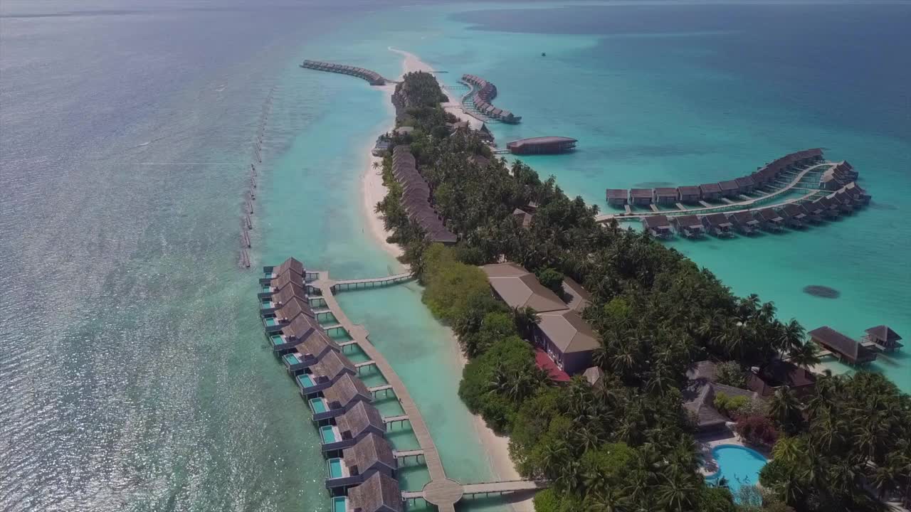 在阳光明媚的一天，无人机向前下降在酒店周围的绿松石海-南马莱环礁，马尔代夫视频素材