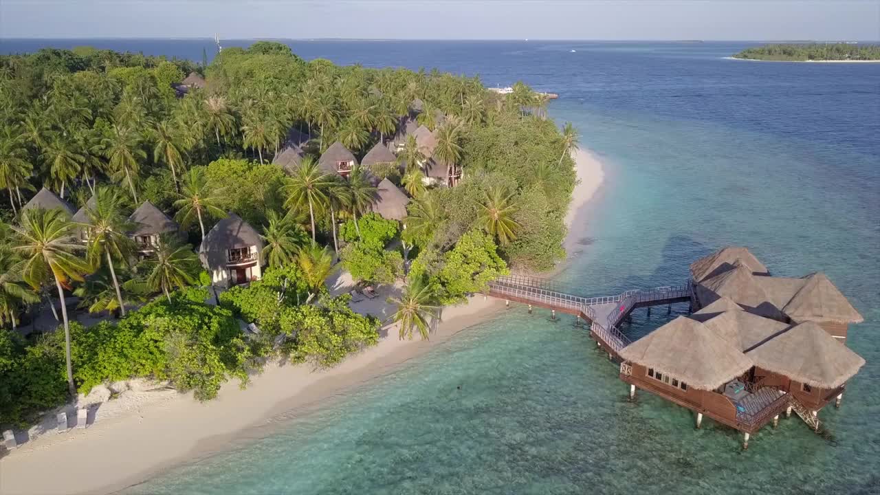 鸟瞰岛屿与豪华度假村的天空，无人机从酒店向后上升在晴朗的一天-南马累环礁，马尔代夫视频下载