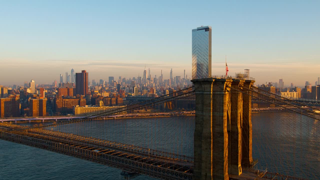 布鲁克林大桥鸟瞰图与遥远的曼哈顿地平线横跨东河和日出。无人机视频与全景轨道和上升的摄像机运动。视频下载