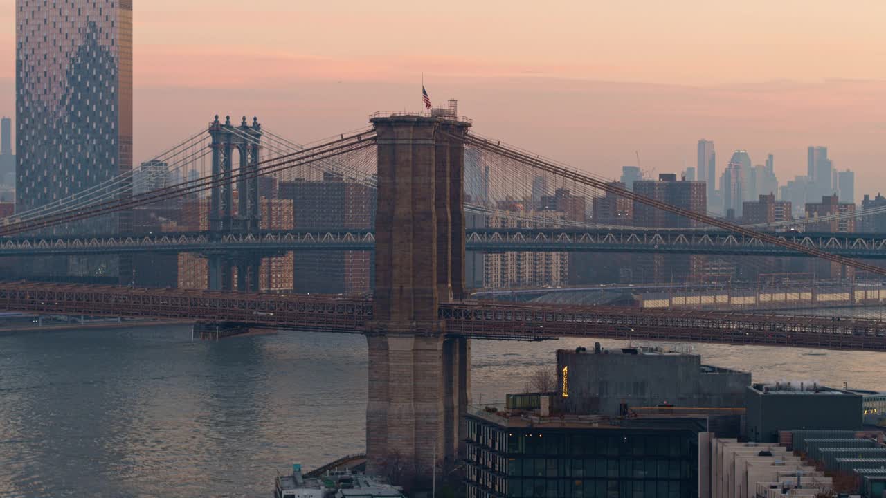 从空中俯瞰布鲁克林大桥，以曼哈顿天际线为背景，在清晨的晨曦中被雾气笼罩着。无人机视频与上升的摄像机运动。视频素材