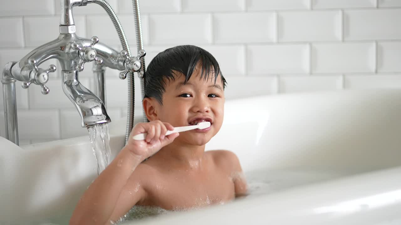 一个亚洲小孩在浴室里刷牙。日常健康和牙科护理的概念视频下载