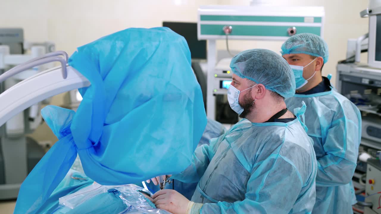 医生进行手术。身穿蓝色防护服的医务人员在诊所的手术室工作。外科手术手术室中的外科手术视频素材