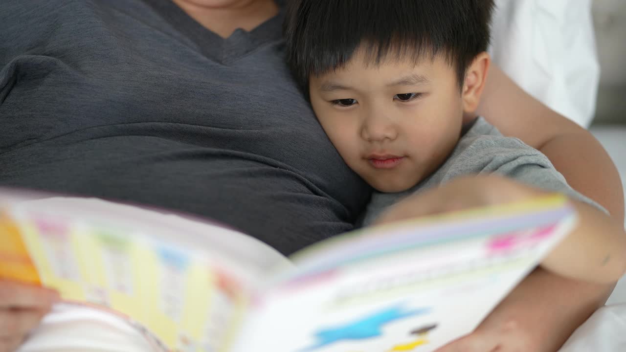 亚洲孩子和妈妈在卧室里读睡前故事。家庭时间的概念视频素材