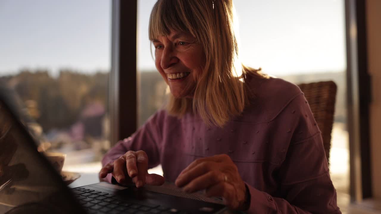 快乐的高级女性使用笔记本电脑。视频下载