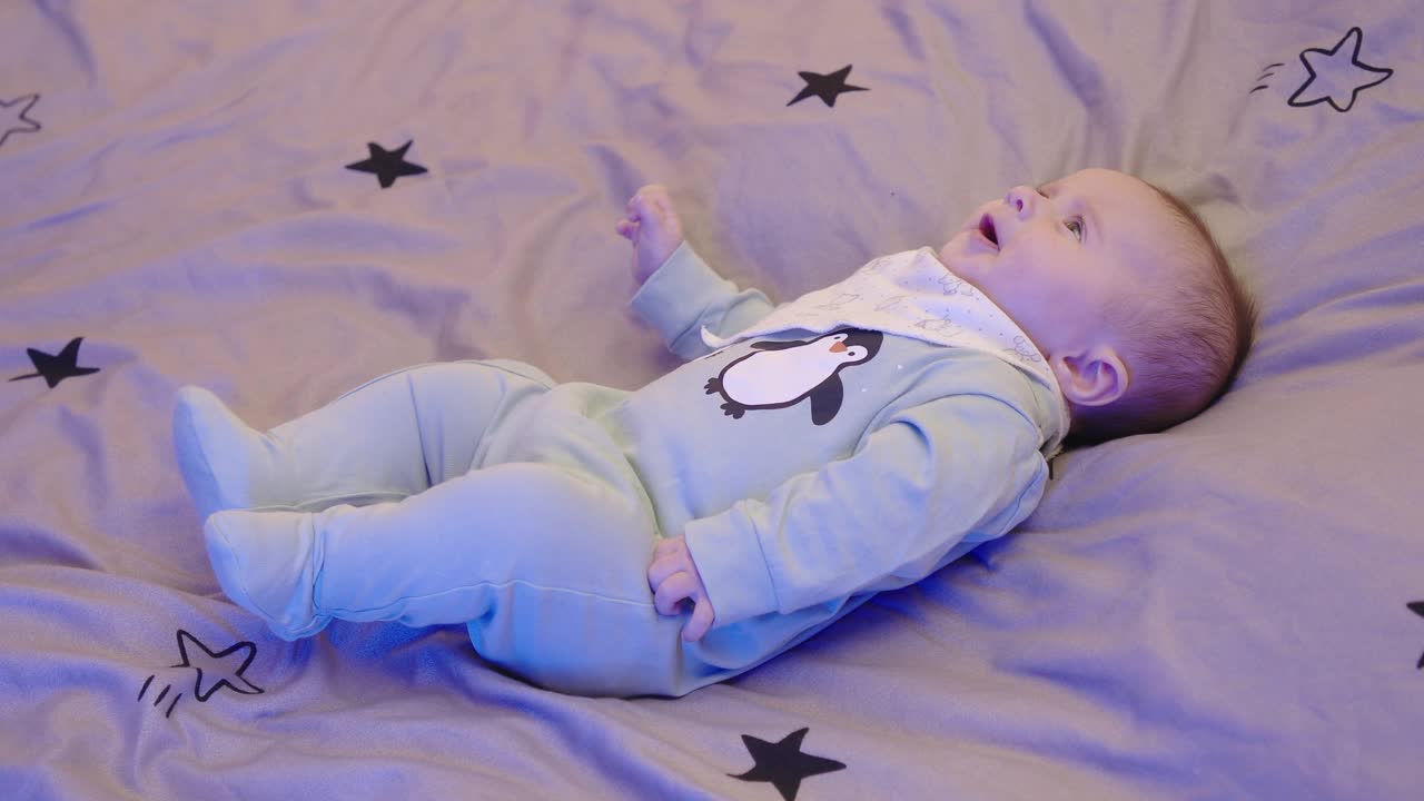 COVID-19大流行期间的新生儿。两个月大的宝宝躺着玩，微笑，四处走动。视频素材