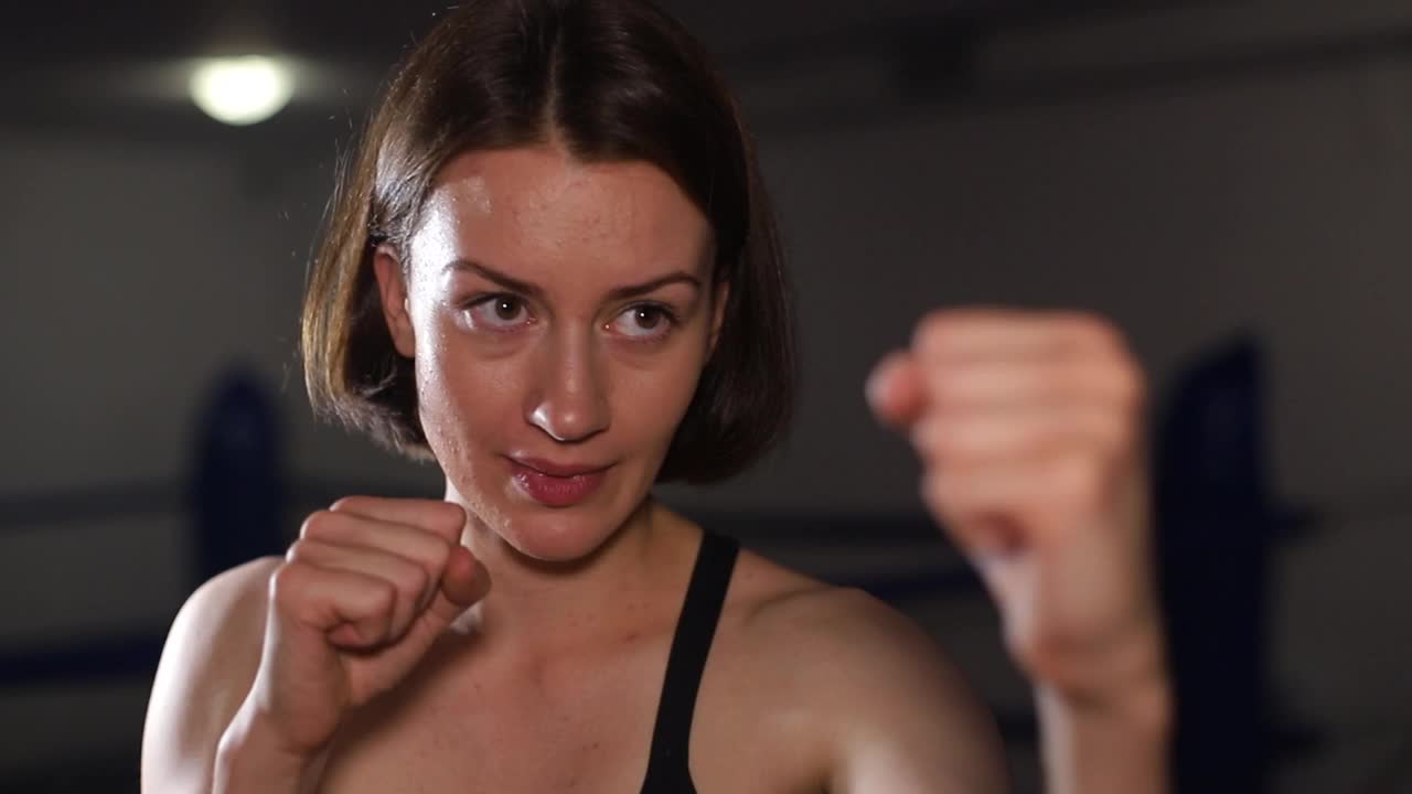 一个梳着马尾辫的女人的肖像，手上缠着特殊的拳击绷带。视频下载