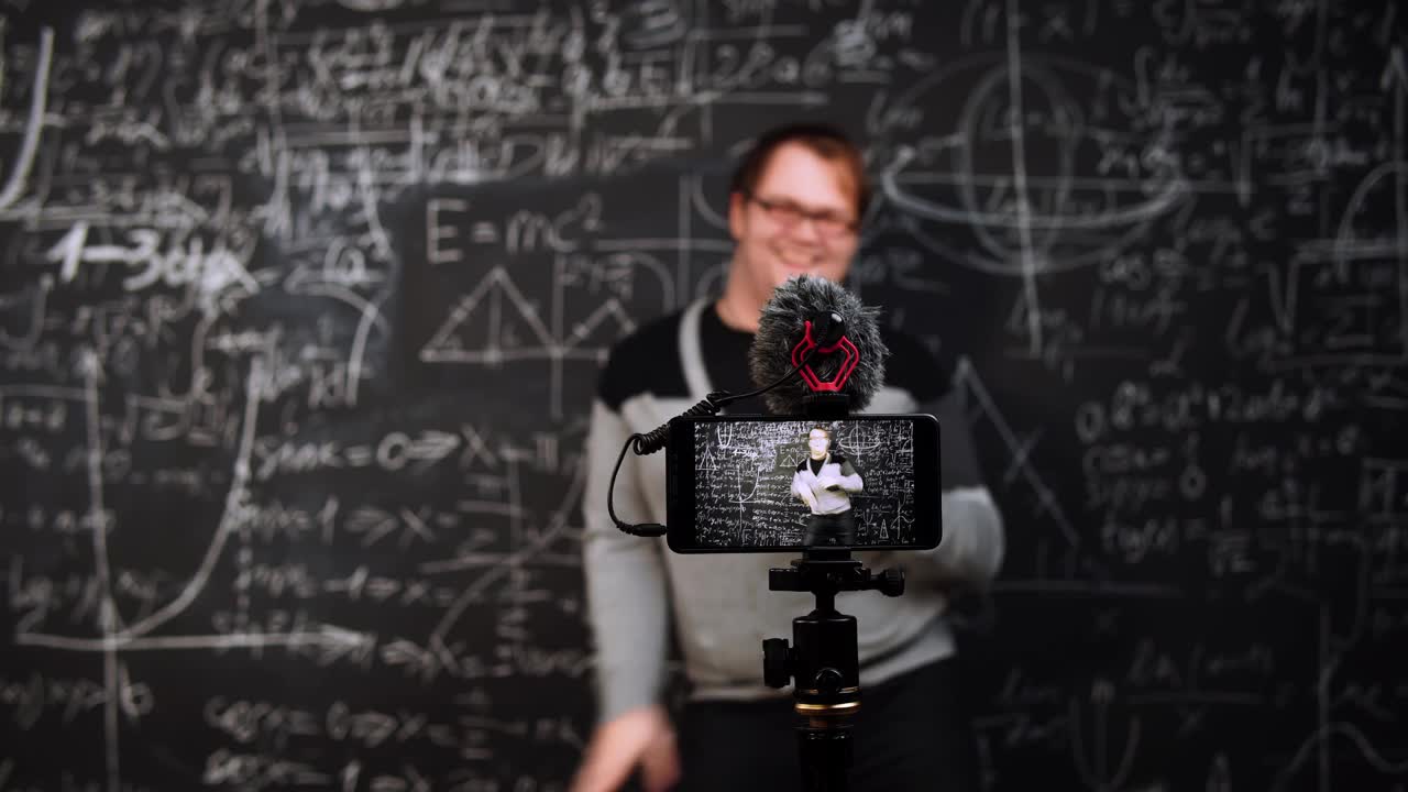代数学老师在黑板背景上跳舞，在移动摄像机前用公式和等式视频下载