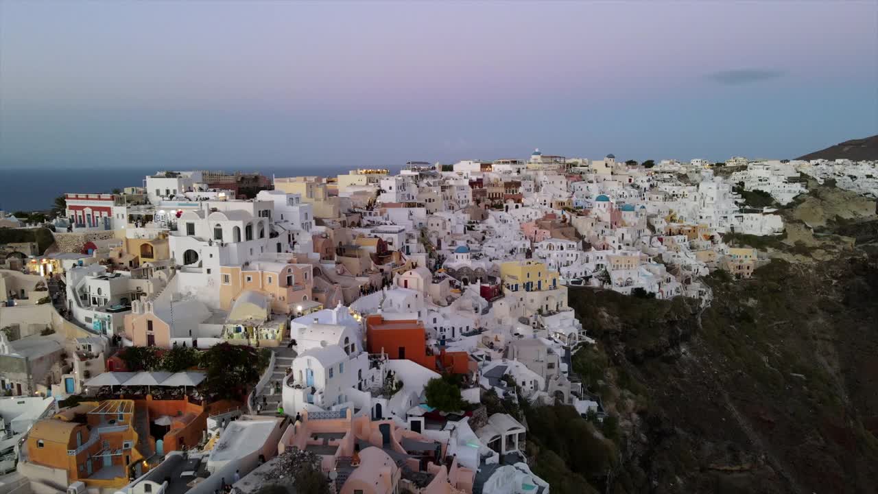航拍的游客探索城市在山上的天空，无人机向后飞行在日落的结构-圣托里尼，希腊视频素材
