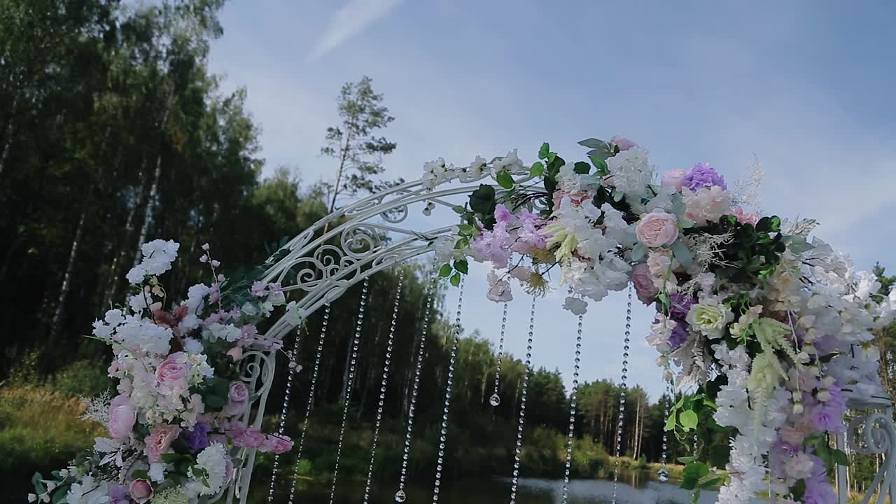美丽的婚礼拱门上装饰着鲜花和其他装饰品。一阵微风吹来。四周都是美丽的大自然视频素材