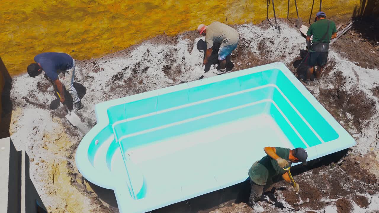 工人在自家后院的洞上安装游泳池的俯视图视频下载