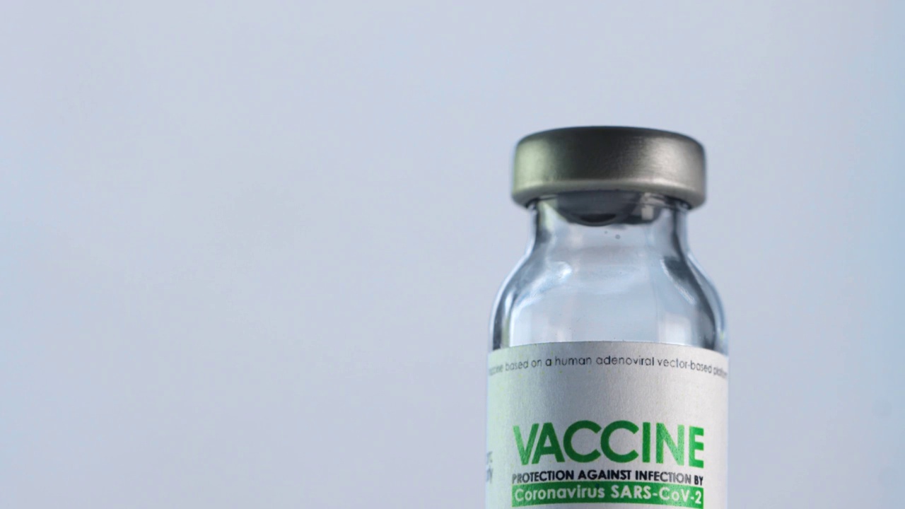 医生在注射前将治疗COVID-19的疫苗瓶装满注射器。大流行疫苗接种的概念。针穿过瓶盖，进入小瓶内。医用手套。宏观的特写镜头视频素材