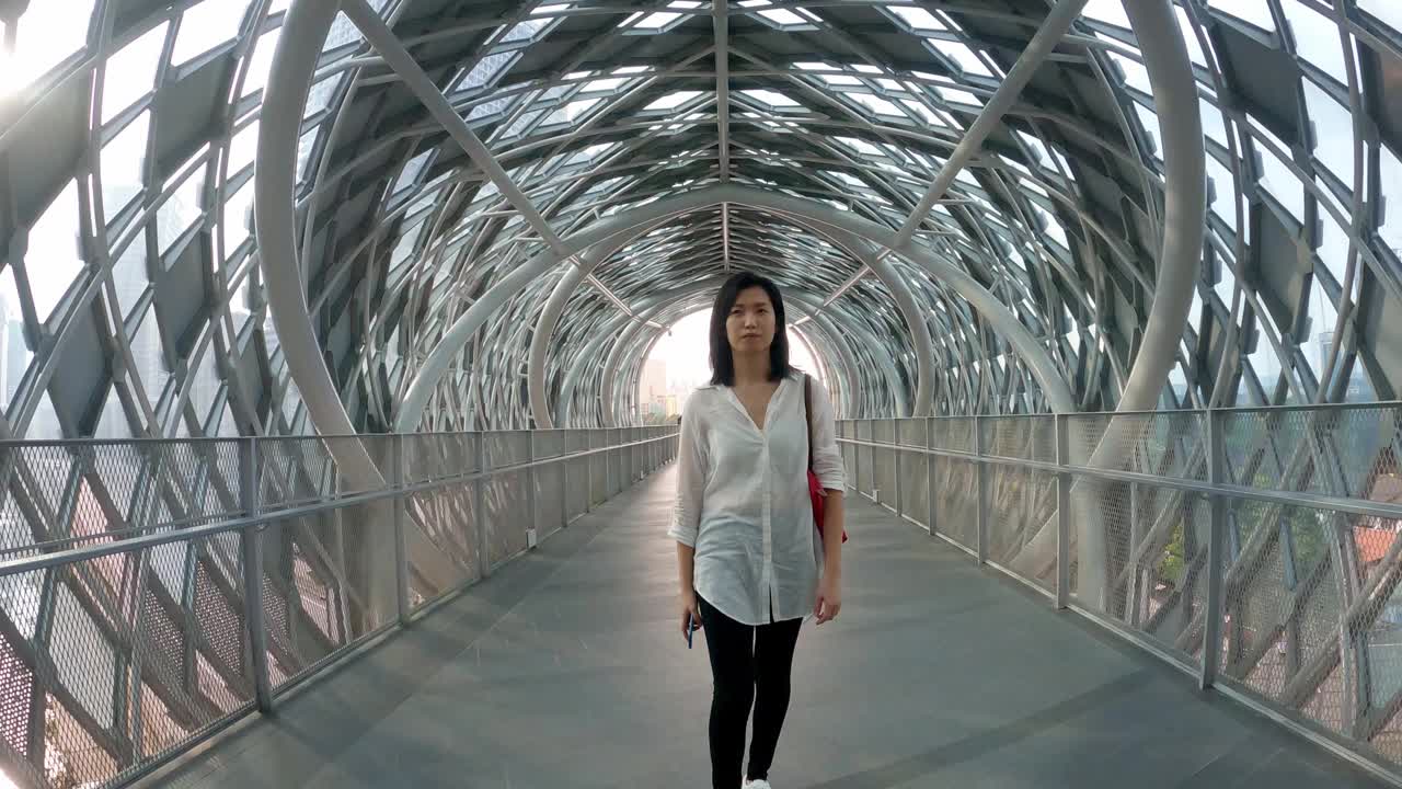 一名亚洲华裔女子在吉隆坡市中心的人行天桥上行走视频素材