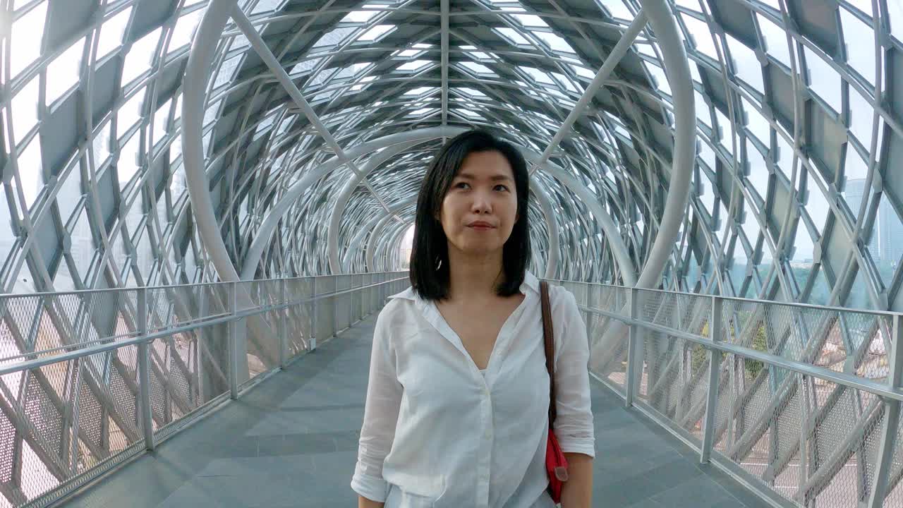 一名亚洲华裔女子在吉隆坡市中心的人行天桥上行走视频素材