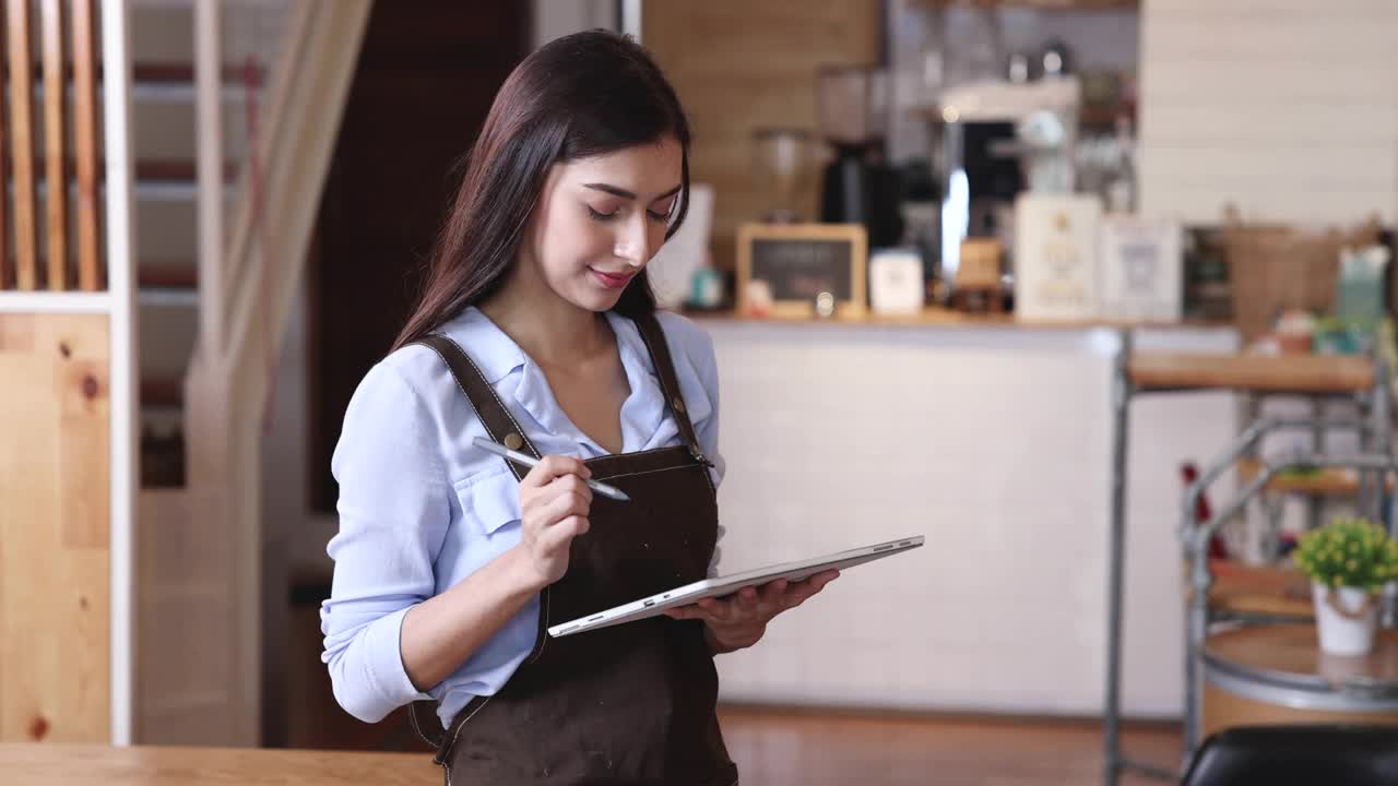 在一家咖啡店，女咖啡师用平板电脑为顾客点菜。视频素材