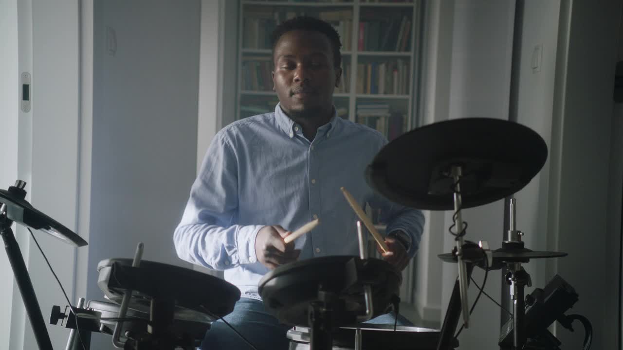 一个非洲裔男子在他的客厅里练习电子鼓。前视图视频下载