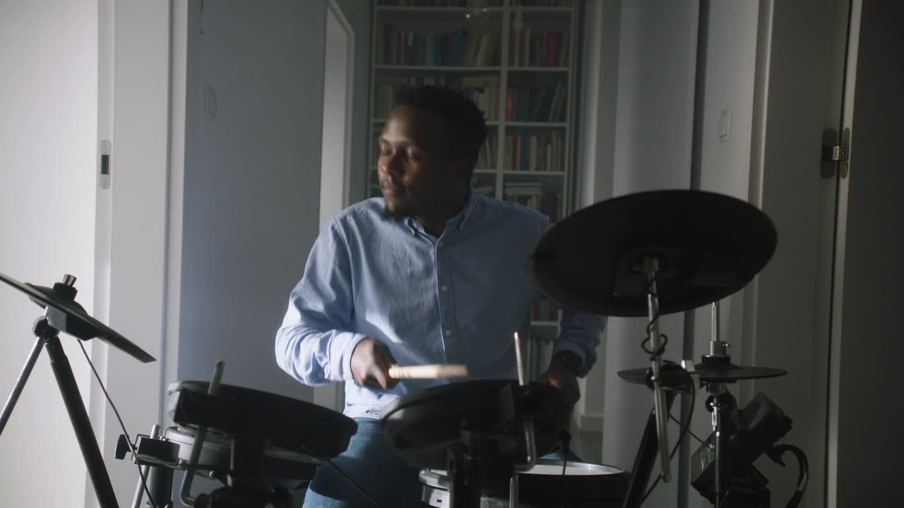 一个非洲裔男子在他的客厅里练习电子鼓。前视图视频下载