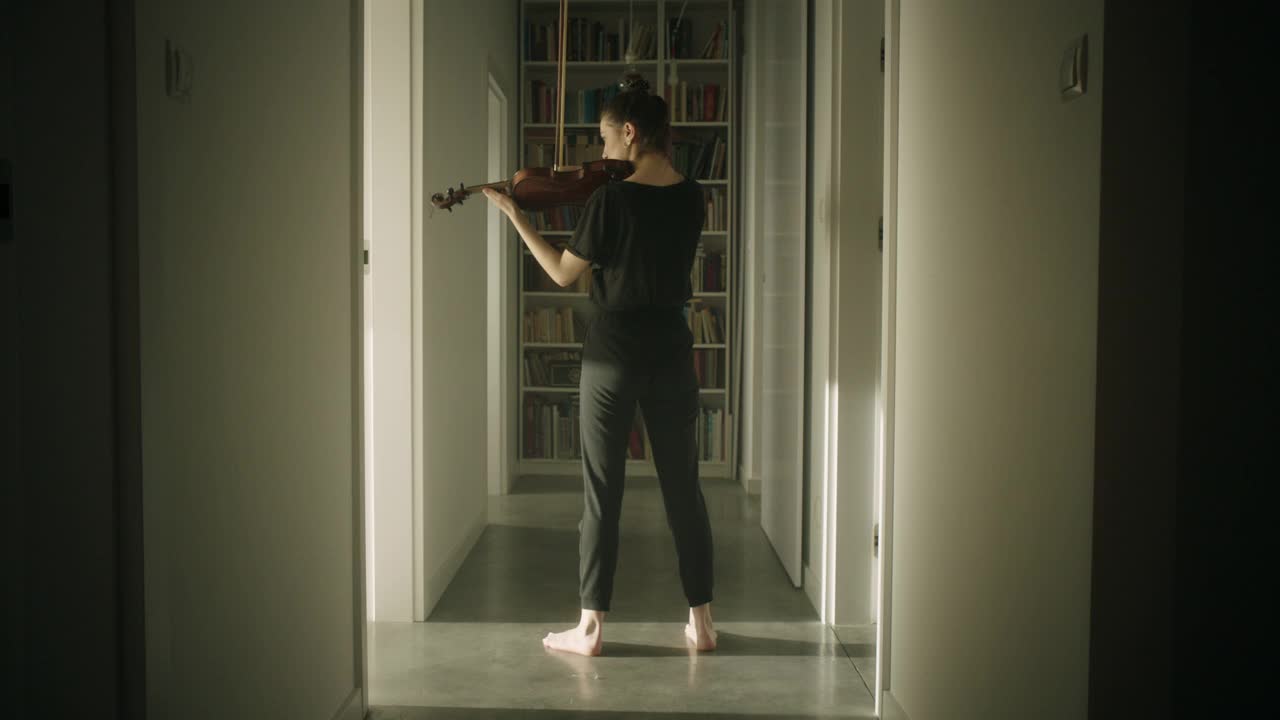 漂亮的年轻女音乐家在走廊里拉小提琴视频下载