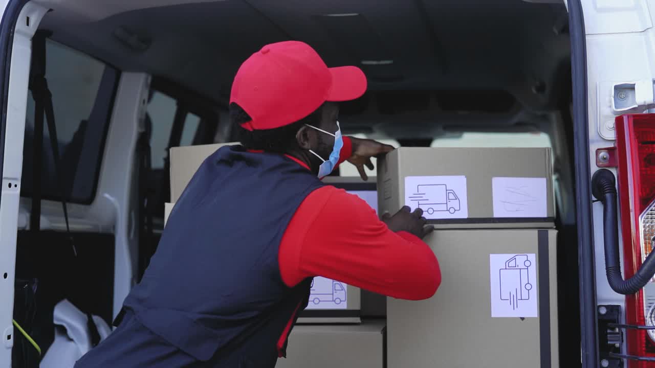 非洲送货员戴着口罩在卡车上装货以避免冠状病毒传播-冠状病毒爆发期间从事快速送货工作的人视频素材