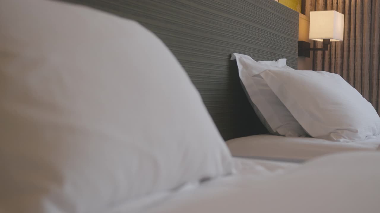 多莉拍摄的美丽休闲白色软枕头和床单卧室舒适放松室内设计家庭室内细节概念4k镜头视频下载