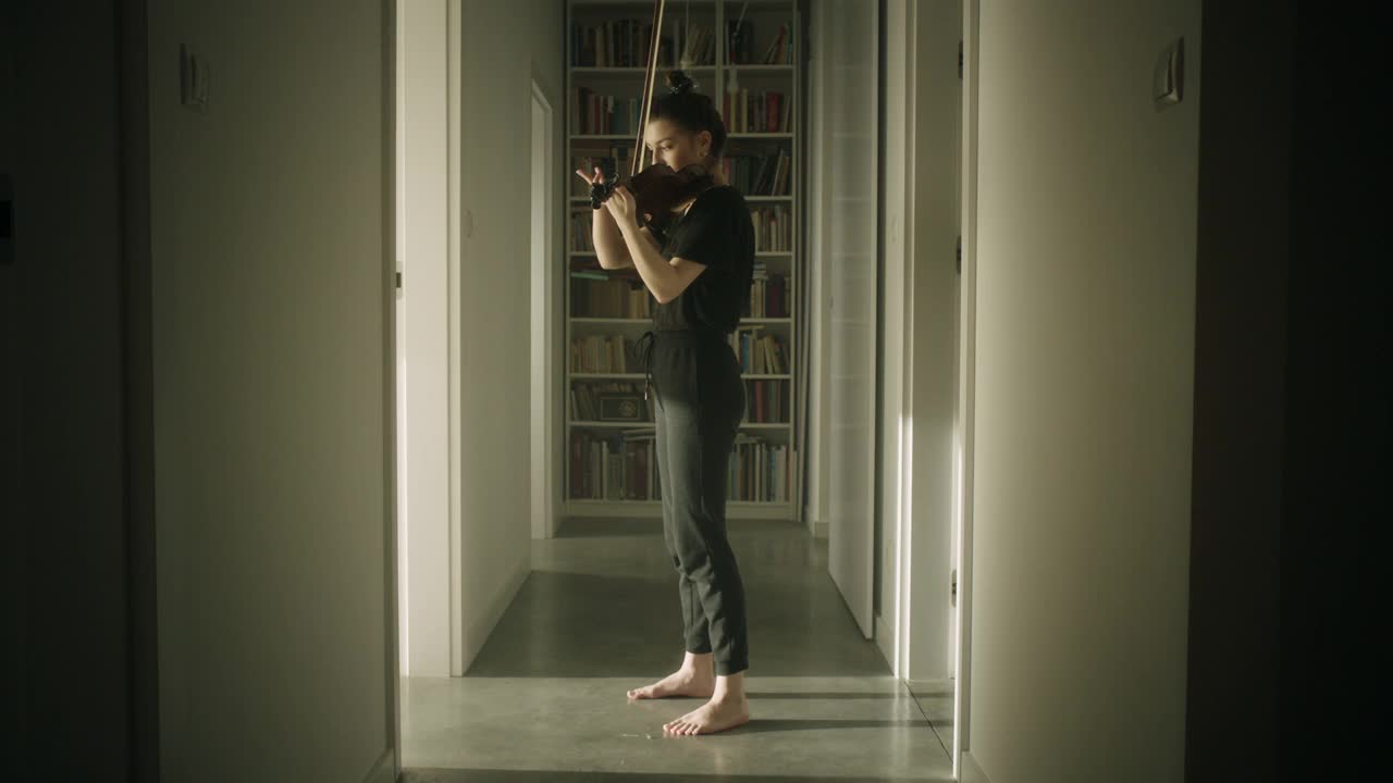 漂亮的年轻女音乐家在走廊里拉小提琴视频素材