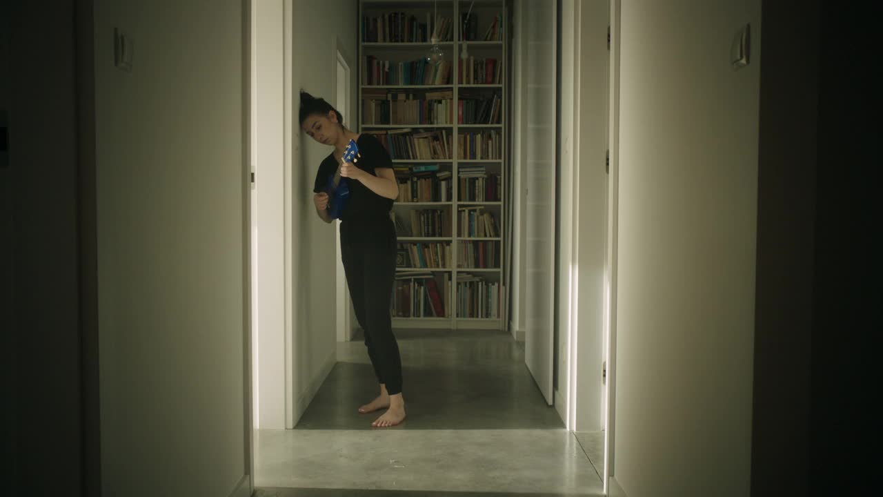 年轻女子在走廊里弹奏尤克里里琴视频下载