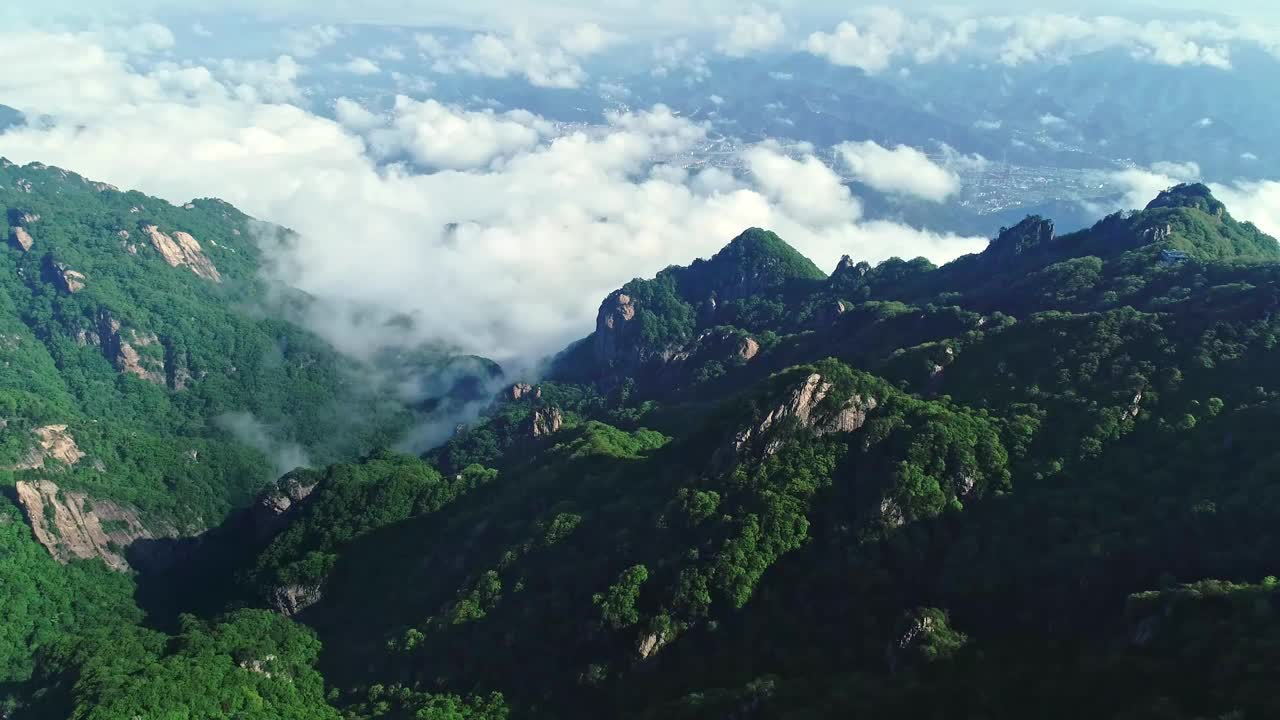 空中拍摄的白云在山峰和一个城镇在河南，中国视频素材