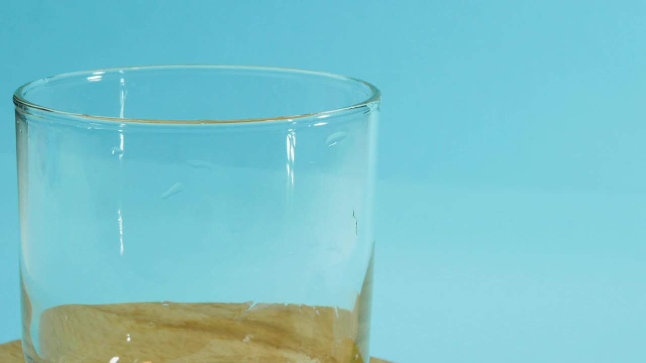 把开菲尔倒进一个在蓝色背景上的玻璃杯里，乳制品，在玻璃杯里开菲尔的特写。新鲜的酸奶。视频素材
