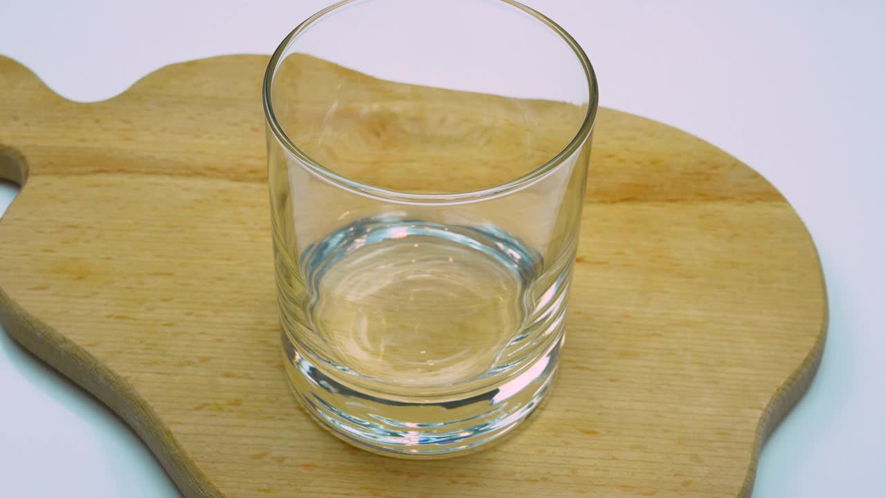白色背景木托盘上的透明玻璃杯里的新鲜酸奶。将酸奶倒入玻璃杯中。乳制品视频素材