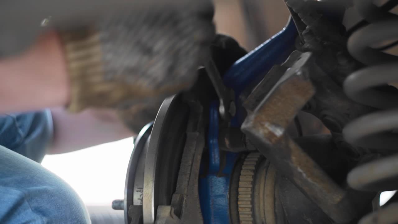 一个人在修理汽车轮子的过程中拧上了一个螺母。路面破损视频素材