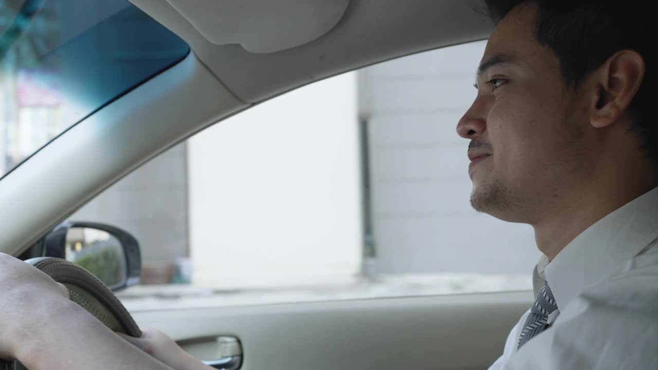 一名亚洲男子早上开车在城市的街道上上班。视频素材