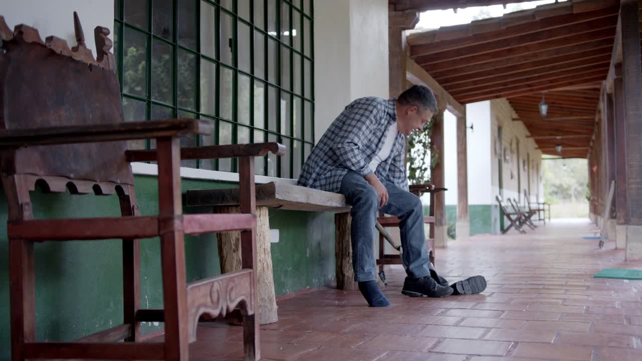 拉丁美洲的一位农民正准备在田里干活，穿上他的橡胶靴子视频素材