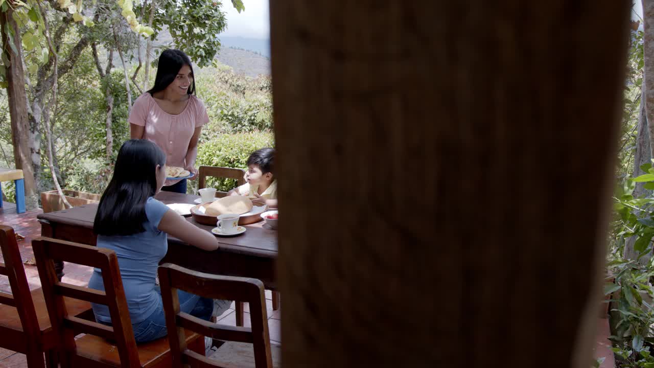 年轻美丽的母亲为她的家人提供美味的传统玉米饼早餐在一个美丽的山景农场视频素材
