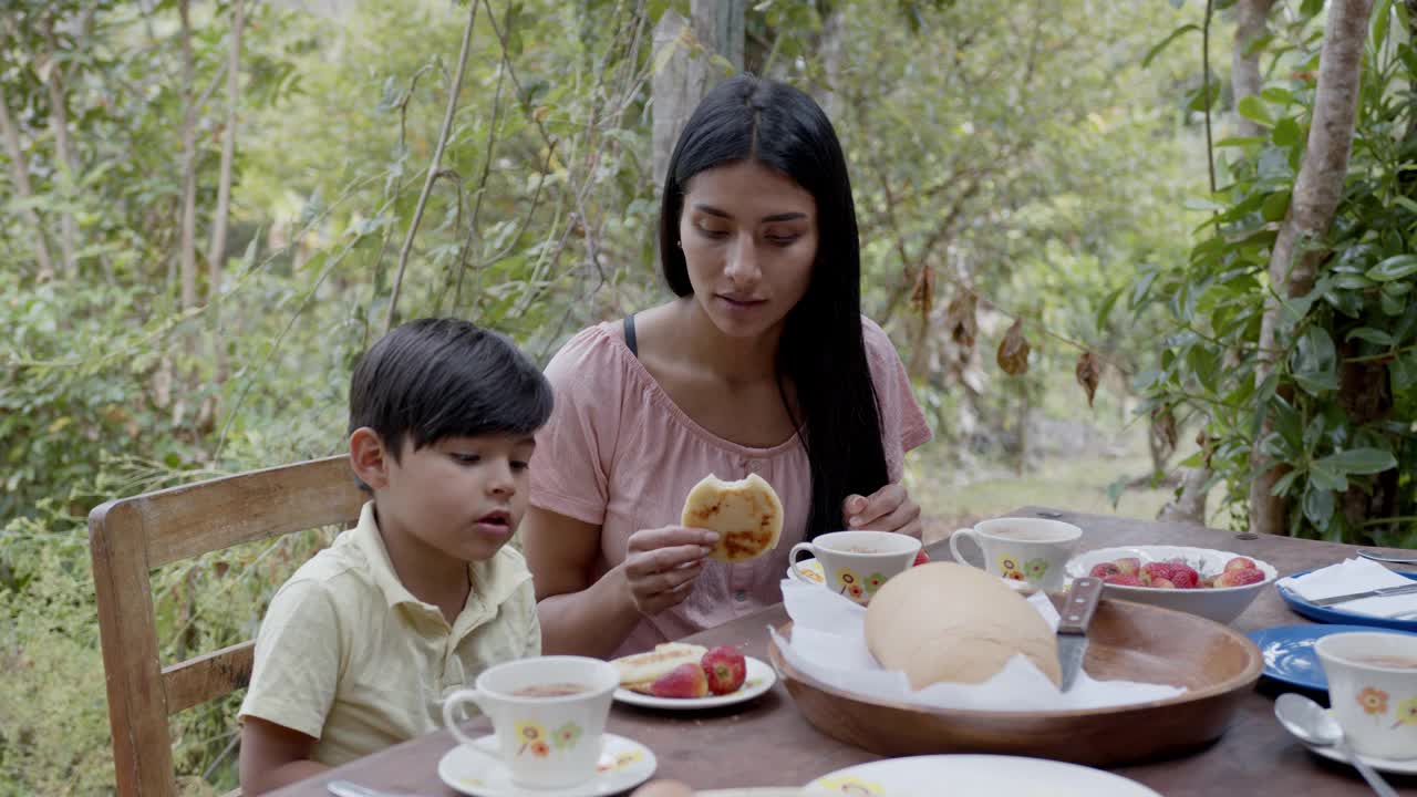 慈祥的母亲和她的儿子在一个农村家庭吃早餐，两人看起来都很高兴视频素材