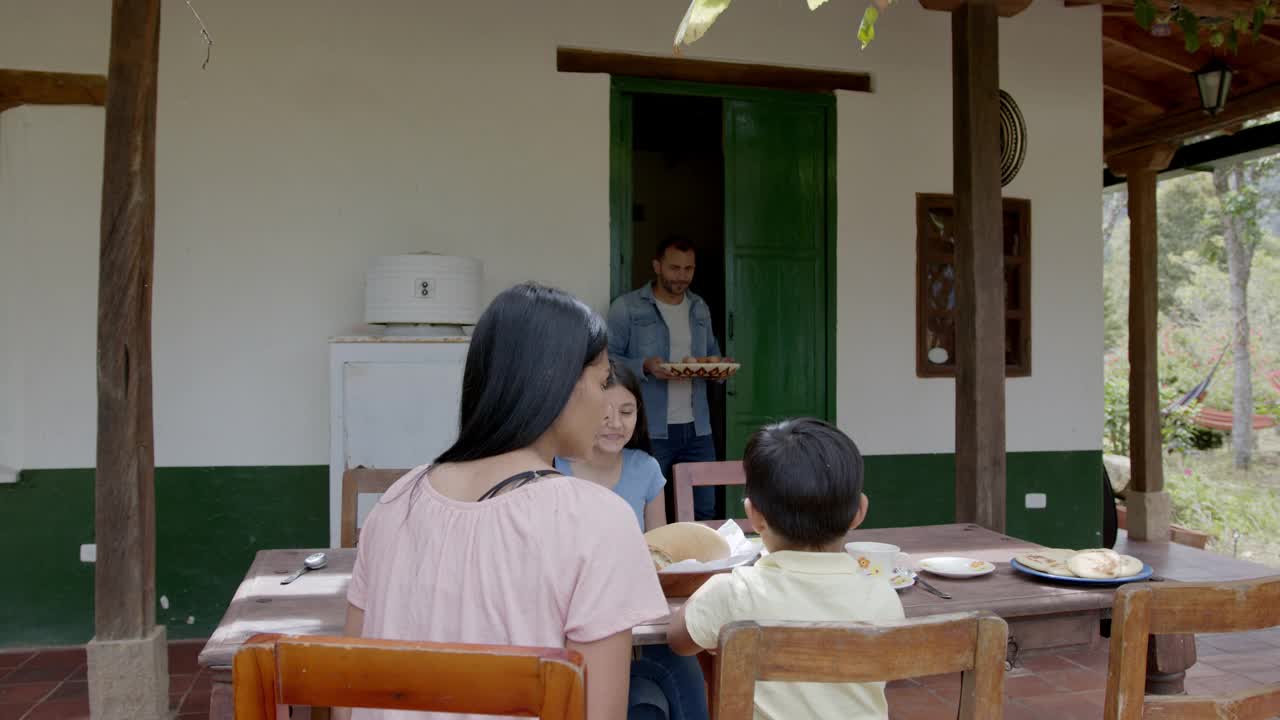 一个幸福的哥伦比亚家庭住在一个农场里，爸爸给他们鸡蛋做早餐视频素材