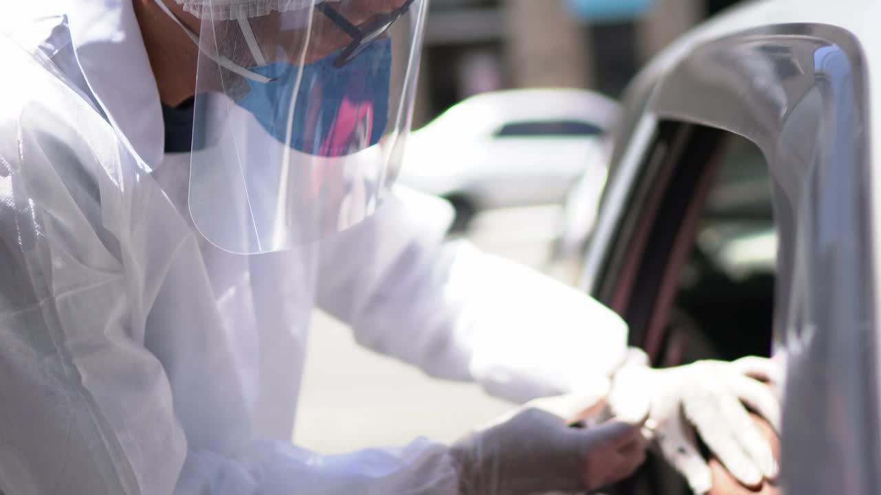 成熟的妇女正在接种疫苗在一个开车穿过-穿着保护性的工作服视频下载