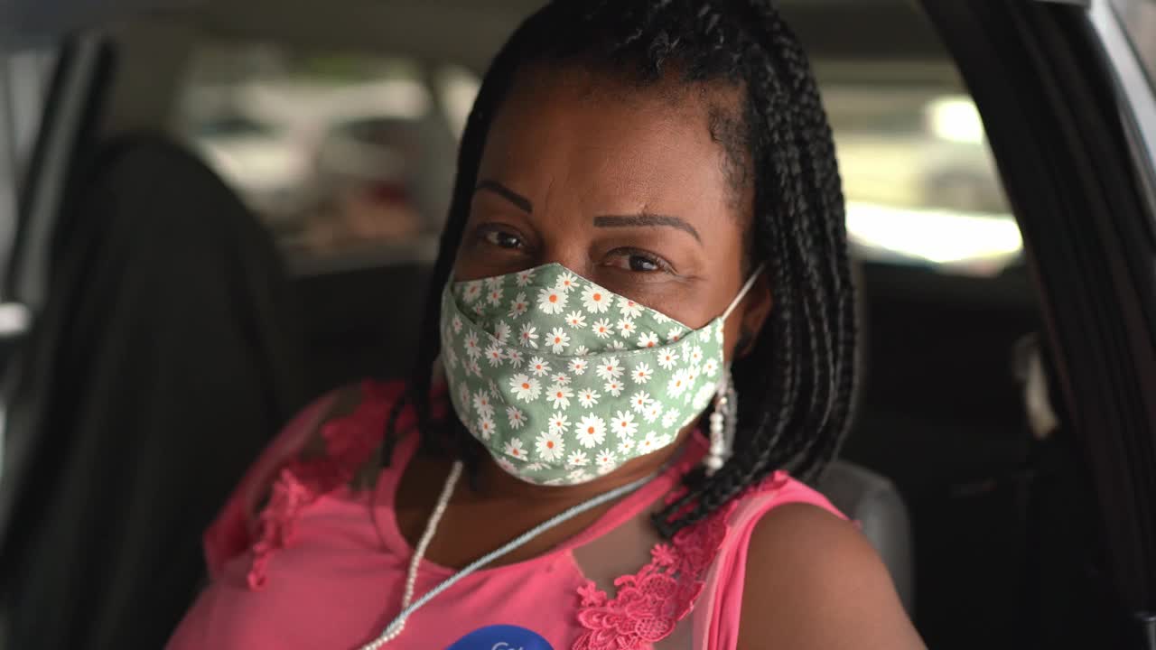 一个快乐的女人在车里的肖像，戴着“接种疫苗”贴纸的面具视频素材