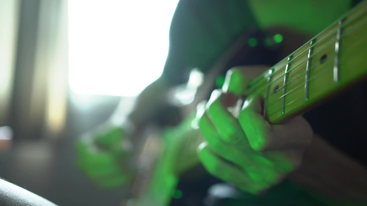一个男人在一个有彩色灯光的房间里弹电吉他视频素材