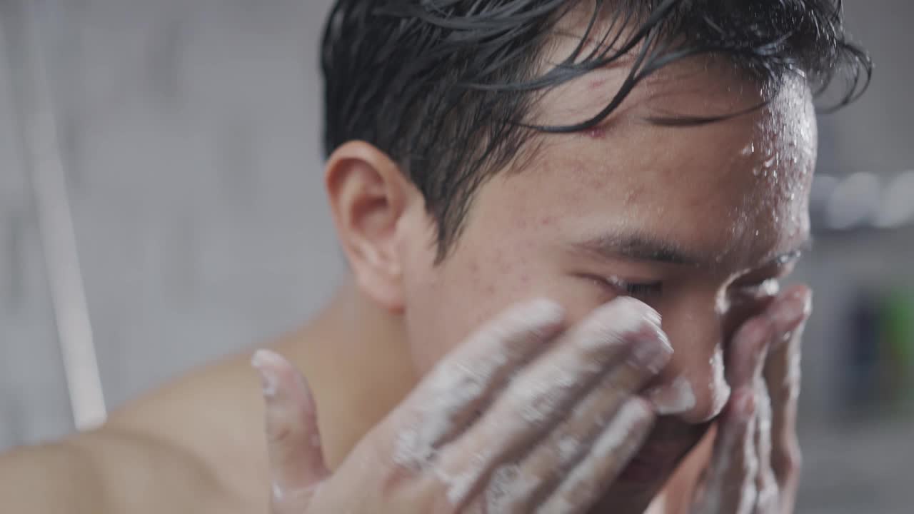一名英俊的亚洲男子正在洗澡并使用面部泡沫视频素材