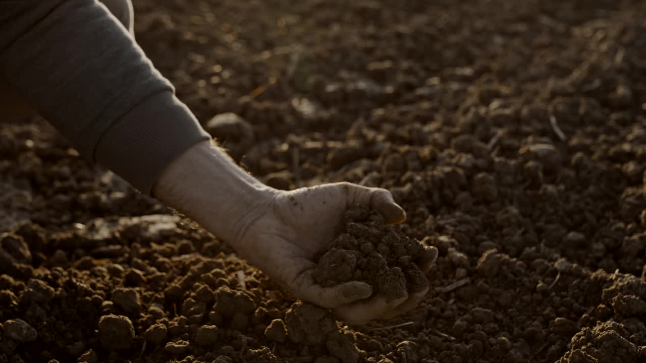 日落时分，农夫的手在田里铲土视频素材