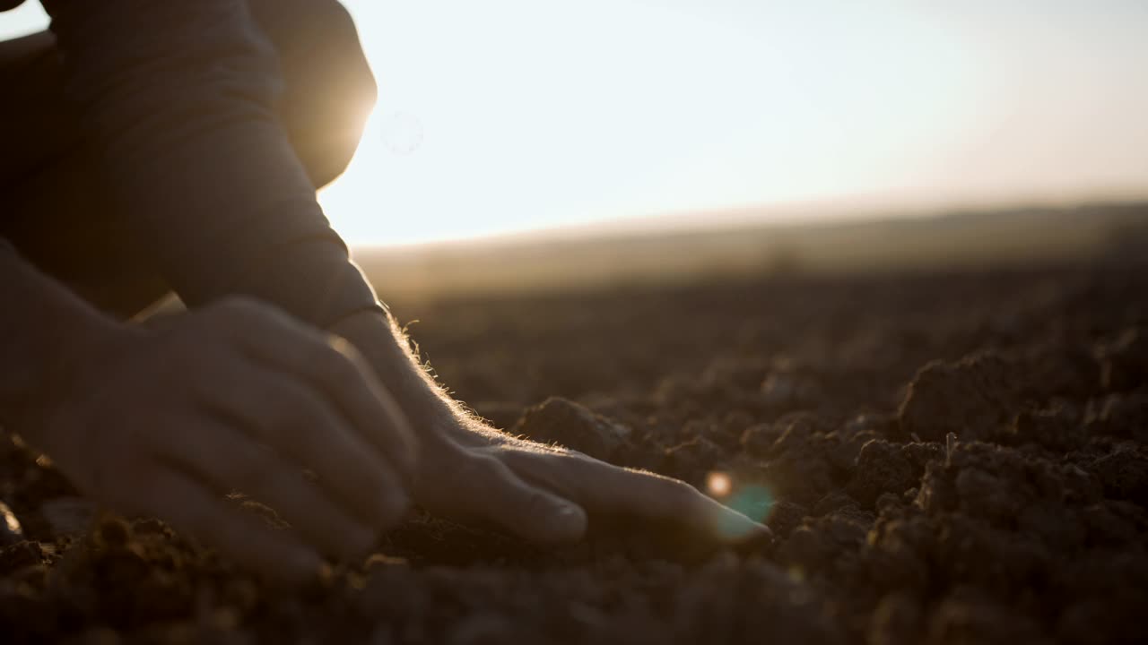 日落时分，农夫的手在田里铲土视频素材