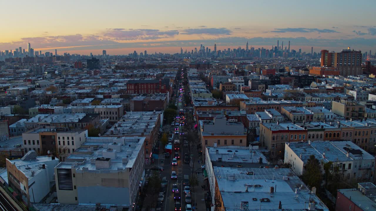 在纽约布鲁克林布什维克住宅区的街道上，夕阳西下，远处的曼哈顿天际线景色尽收眼底。无人机视频与平移摄像机运动。视频素材