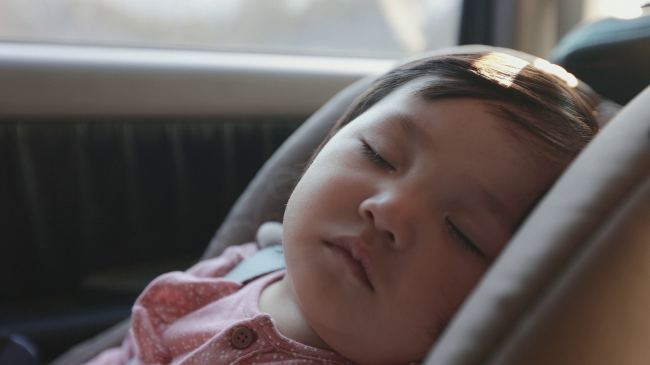 靠近可爱的亚洲幼童女孩坐在汽车座椅和睡觉，而与家人旅行在慢动作镜头。视频下载