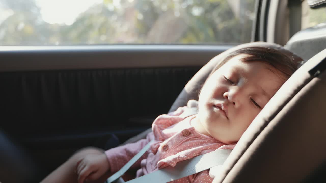 慢动作可爱的亚洲学步女孩坐在汽车座椅和睡觉，而与家人旅行。视频素材