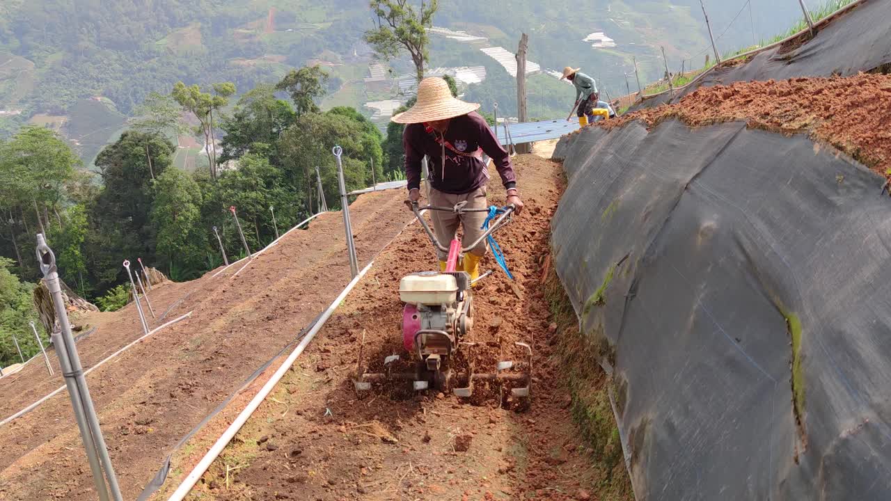 亚洲男性农民用手摇拖拉机在山坡上犁地视频下载
