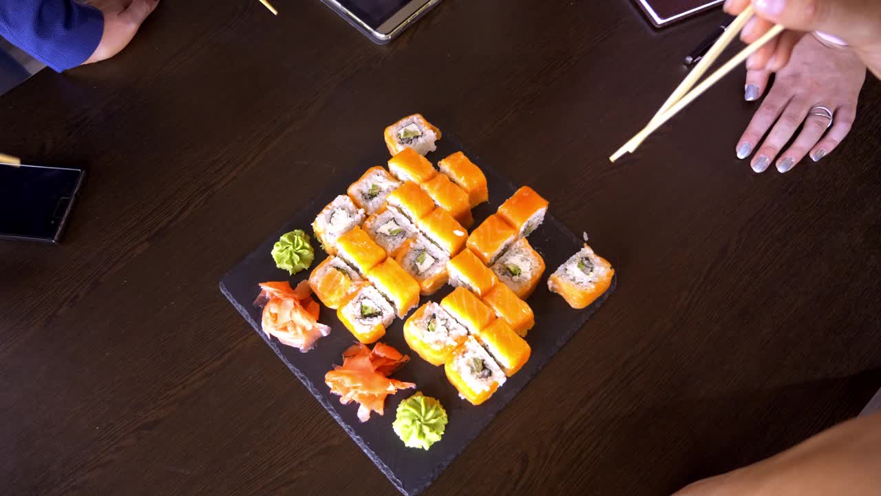 餐馆桌子上的一套寿司卷。一群朋友用竹签吃寿司卷。视频素材