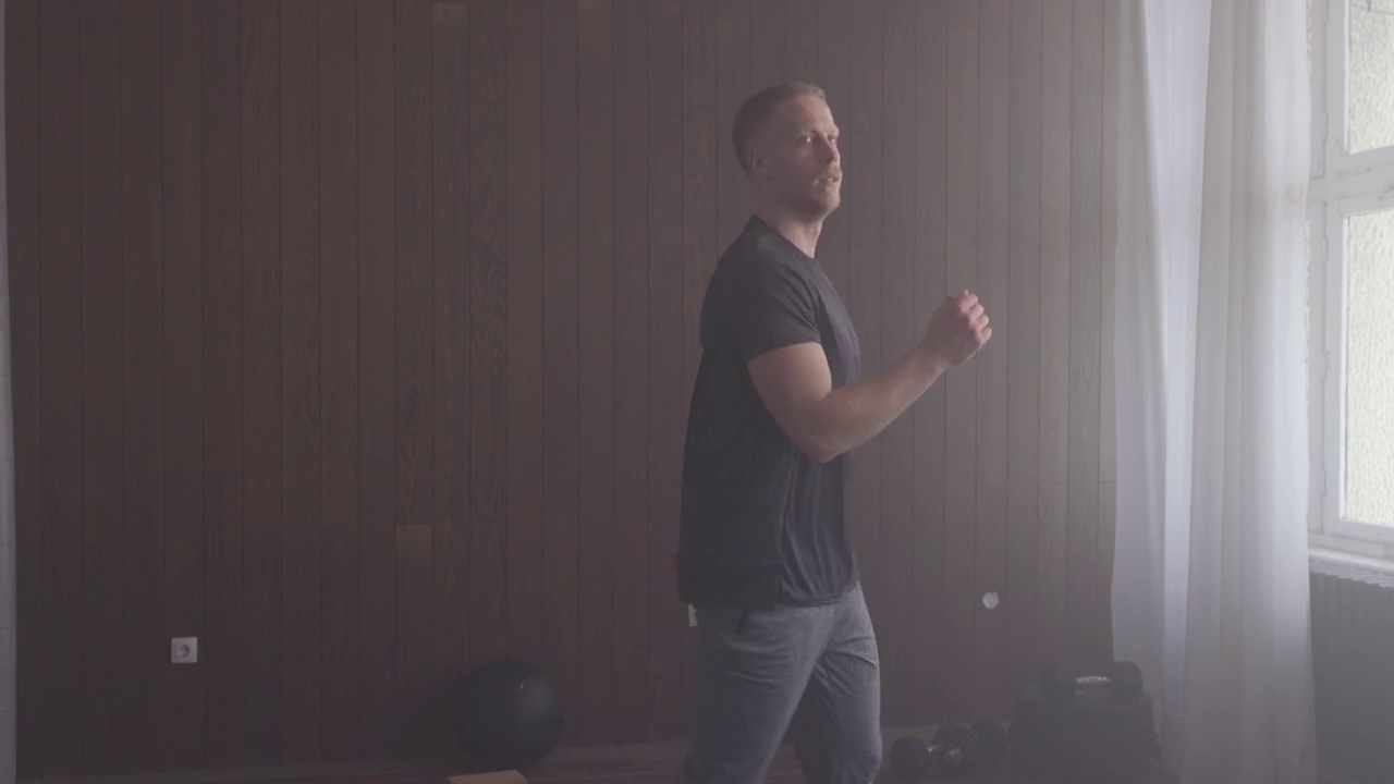 有氧运动:英俊的运动员在室内健身房里做高膝盖运动(复制空间)视频下载