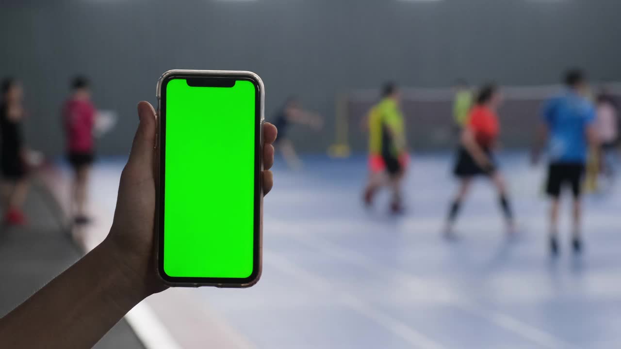 手显绿色屏幕智能手机在室内体育馆视频素材